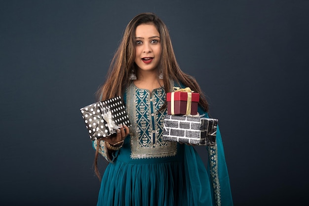 Retrato de uma jovem sorridente feliz Menina segurando uma caixa de presentes em um fundo cinza