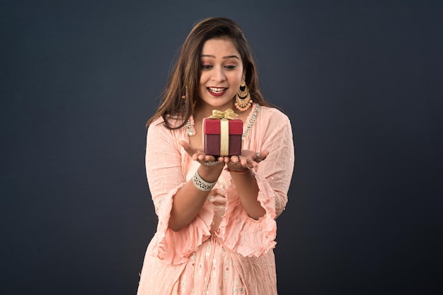 Retrato de uma jovem sorridente feliz Menina segurando uma caixa de presentes em um fundo cinza