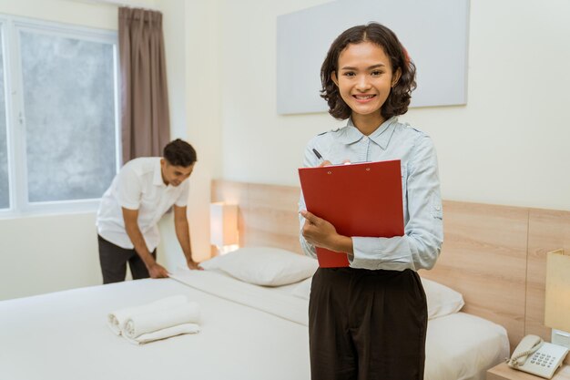 Foto retrato de uma jovem sorridente lendo um livro sentada na cama em casa