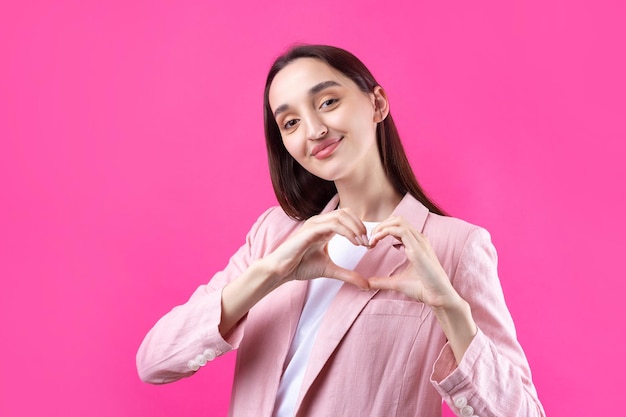 Retrato de uma jovem sorridente mostrando o gesto do coração com os dedos isolados sobre o fundo pikn