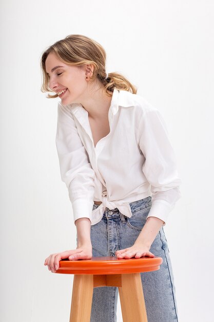 Retrato de uma jovem sorridente mulher caucasiana com cabelos longos, posando em camisa, jeans azul, isolado no branco