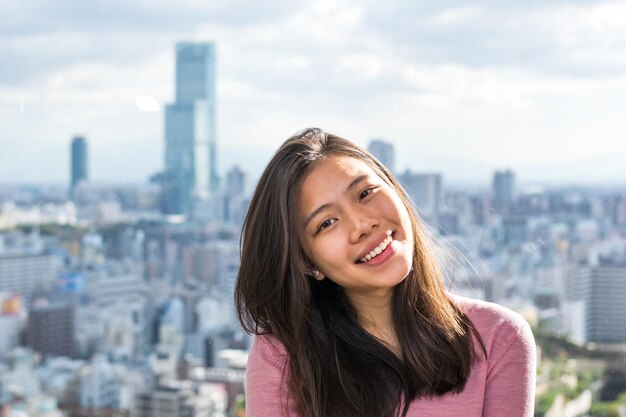 Foto retrato de uma jovem sorridente na cidade contra o céu