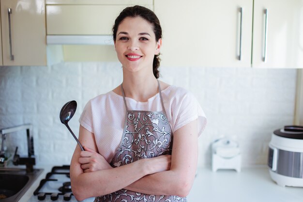 Retrato de uma jovem sorridente na cozinha com uma concha nas mãos