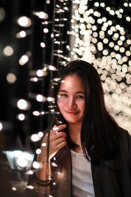 Retrato de uma jovem sorridente por luzes iluminadas à noite