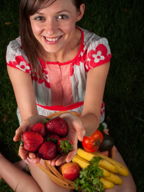 Foto retrato de uma jovem sorridente segurando legumes na cesta.