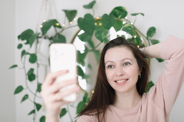 Retrato de uma jovem sorridente segurando smartphone fazendo selfie ou bate-papo por vídeo