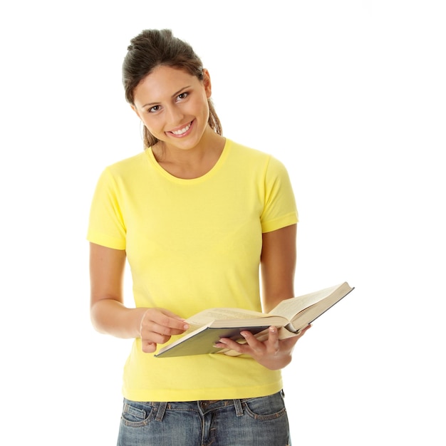 Foto retrato de uma jovem sorridente segurando um livro enquanto está de pé contra um fundo branco