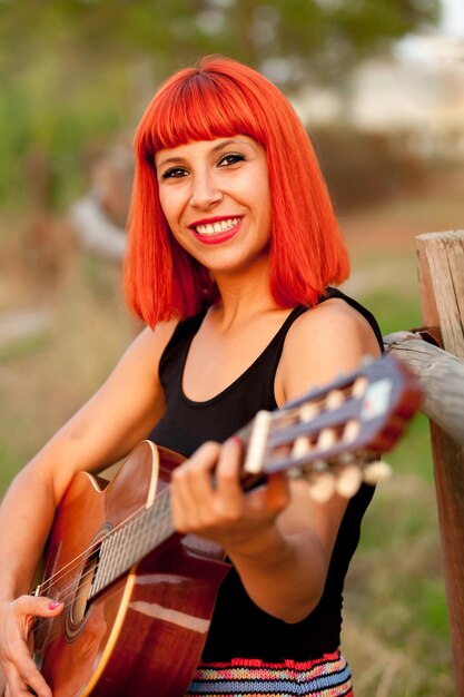 Foto retrato de uma jovem sorridente tocando guitarra