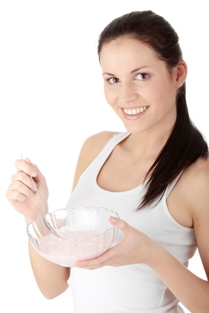 Foto retrato de uma jovem sorridente tomando o café da manhã de uma tigela contra um fundo branco