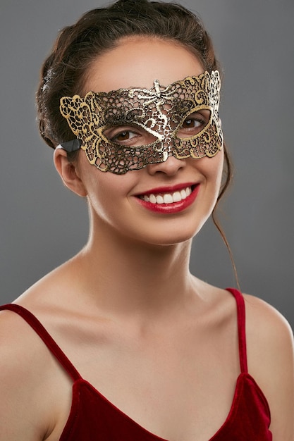 Retrato de uma jovem sorridente usando máscara em fundo cinzento