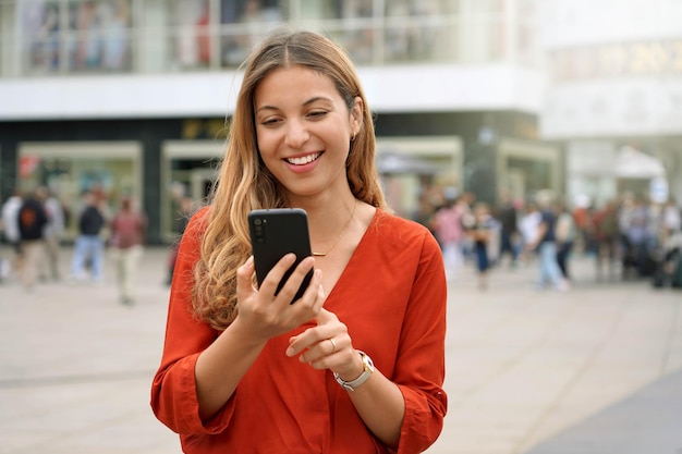 Retrato de uma jovem sorridente usando um aplicativo de smartphone em Berlim, Alemanha