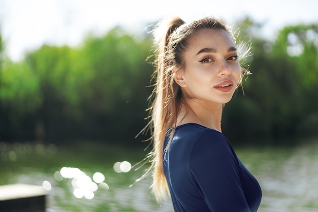 Retrato de uma jovem sorridente, vestindo roupas esportivas no parque matinal