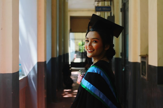 Foto retrato de uma jovem sorridente vestindo um vestido de formatura de pé no corredor do edifício