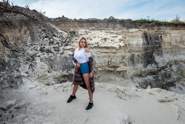 Retrato de uma jovem surpreendente vestindo um casaco de pele em uma pedreira de areia vazia