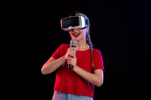 Retrato de uma jovem tocando vr e cantando na parede escura