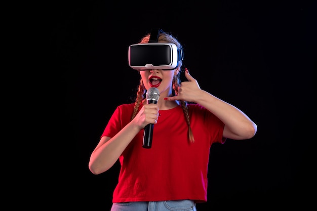 Retrato de uma jovem tocando vr e cantando na parede escura