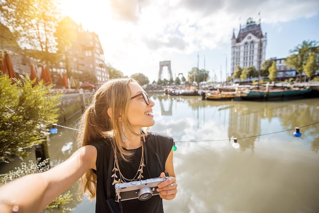 Retrato de uma jovem turista com fotocâmera em pé no antigo porto da cidade de Rotterdam.