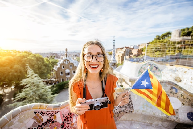 Retrato de uma jovem turista em um vestido vermelho com a bandeira da catalunha visitando o famoso parque guell em barcelona