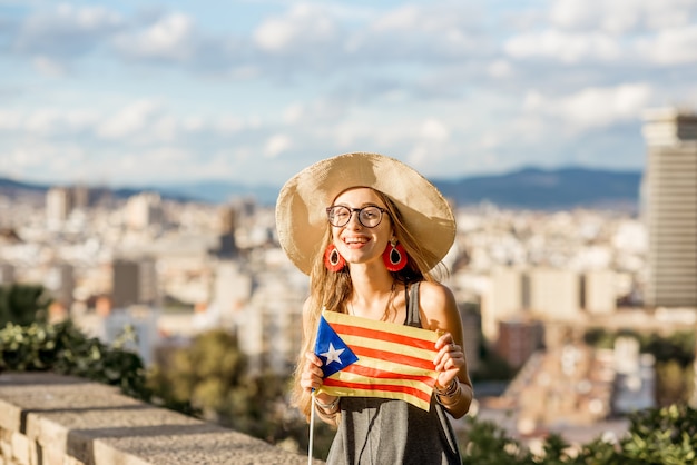 Retrato de uma jovem turista sentada com a bandeira da Catalunha no fundo da cidade de Barcelona