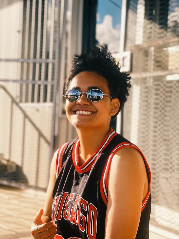 Foto retrato de uma jovem usando óculos de sol de pé ao ar livre