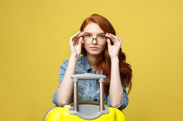 Foto retrato de uma jovem usando óculos de sol de pé contra um fundo amarelo