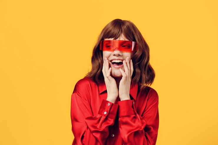 Foto retrato de uma jovem usando óculos de sol enquanto está de pé contra um fundo amarelo