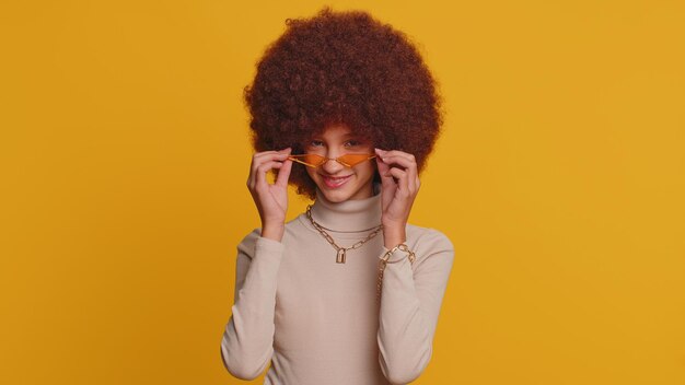 Foto retrato de uma jovem usando óculos de sol enquanto está de pé contra um fundo amarelo