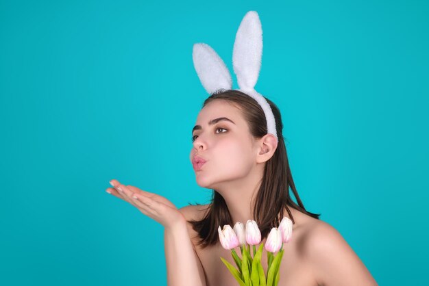 Retrato de uma jovem usando orelhas de coelho segurando ovos de páscoa sobre fundo isolado no estúdio
