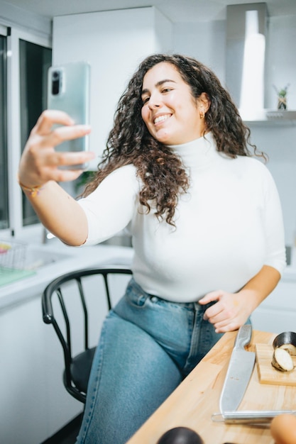 Foto retrato de uma jovem usando um telefone móvel enquanto está sentada em casa