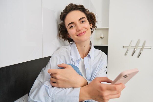 Retrato de uma jovem usando um telefone móvel enquanto está sentada em casa