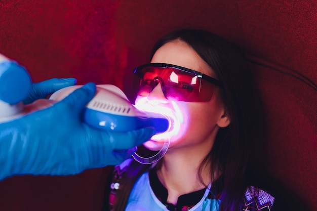 Retrato de uma jovem visitando o consultório do dentista para branquear os dentes com fotopolímero