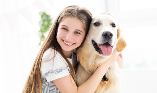 Retrato de uma linda adolescente abraçando lindo cachorro dentro de casa