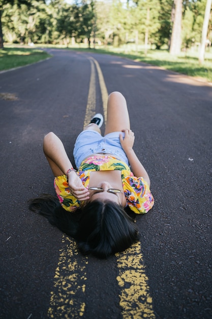 Foto retrato de uma linda adolescente deitada na estrada