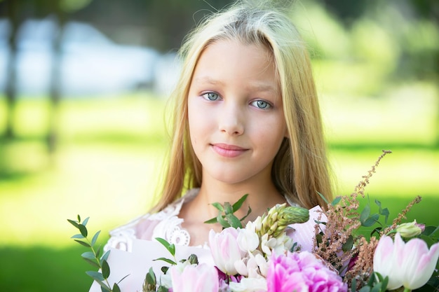 Retrato de uma linda adolescente loira com um buquê de flores