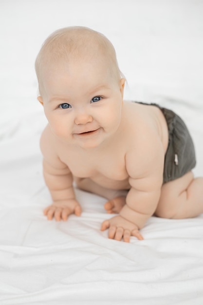 Retrato de uma linda criança de bebê querubim de olhos cinzentos e sorridente usando calças cinzentas em pé
