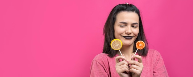 Retrato de uma linda e doce mulher alegre com cabelos castanhos lisos segurando um pirulito perto dos olhos