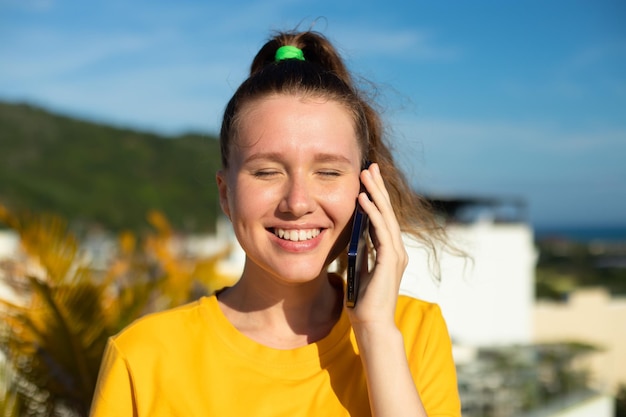 Retrato de uma linda e feliz jovem mulher positiva está falando em seu telefone celular ligando