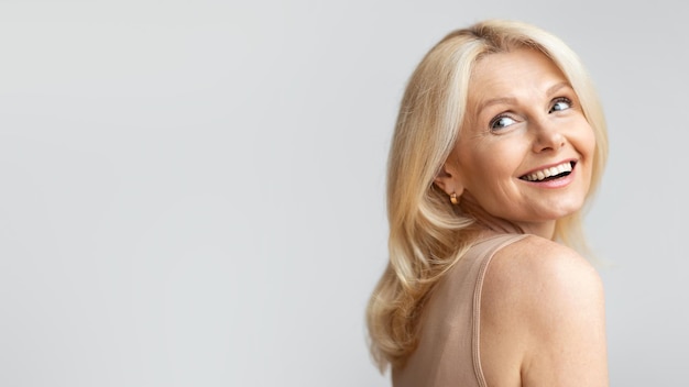 Retrato de uma linda e feliz mulher sênior olhando para o espaço livre e sorrindo posando sobre a luz