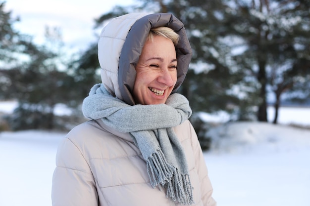 Retrato de uma linda e idosa idosa aposentada em idade está se divertindo com a neve ao ar livre na floresta ou no parque em um dia frio de inverno sorrindo e aproveitando o clima