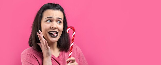 Retrato de uma linda e linda mulher alegre com cabelos castanhos lisos tentando morder o natal de cana-de-doce vermelho