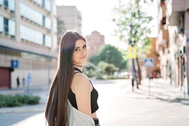 Retrato de uma linda estudante casual sorridente, sonhadora, olhando para a câmera na rua Jovem mulher caucasiana com cabelo comprido