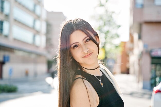 Retrato de uma linda estudante casual sorridente, sonhadora, olhando para a câmera na rua Jovem mulher caucasiana com cabelo comprido