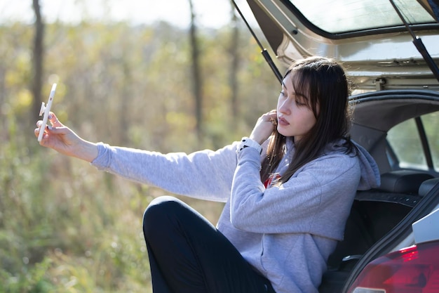 Retrato de uma linda garota ao ar livre que usa um smartphone compartilha conteúdo digital