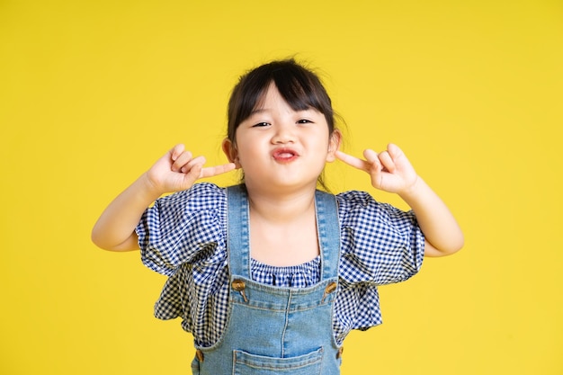 Retrato de uma linda garota asiática isolada em fundo amarelo