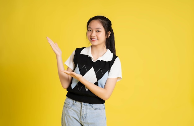 Retrato de uma linda garota asiática posando em um fundo amarelo