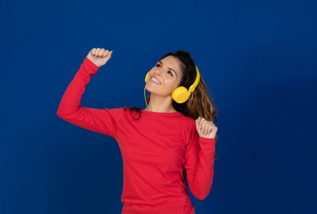 Retrato de uma linda garota caucasiana com cabelos cacheados e fones de ouvido, ouvindo música isolada em uma parede branca