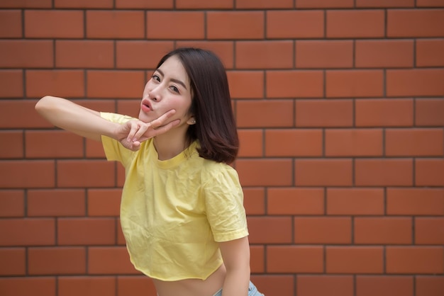 Retrato de uma linda garota chique asiática posar para tirar uma foto na parede de tijolosEstilo de vida do povo adolescente da TailândiaConceito feliz de mulher moderna