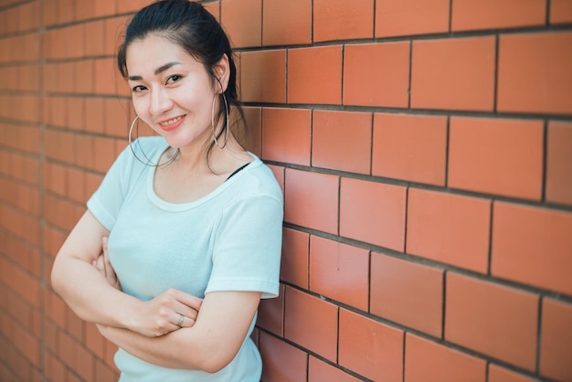 Retrato de uma linda garota chique asiática posar para tirar uma foto na parede de tijolosEstilo de vida do povo adolescente da TailândiaConceito feliz de mulher moderna