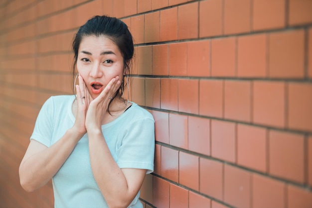 Retrato de uma linda garota chique asiática posar para tirar uma foto na parede de tijolosEstilo de vida do povo adolescente da TailândiaConceito feliz de mulher moderna