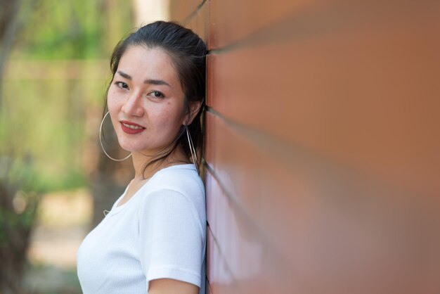 Retrato de uma linda garota chique asiática posar para tirar uma foto na parede de tijolosEstilo de vida do povo adolescente da TailândiaConceito feliz de mulher moderna